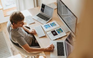 A young man is working remotely at a desk in his in-home office.