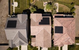 Overhead sky view of three homes with solar panels installed on top of the roofs.