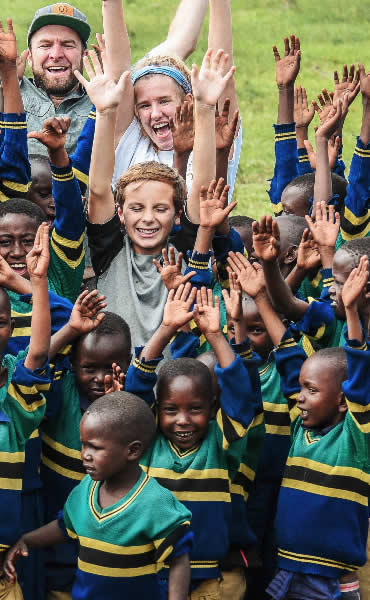 Children in uniforms celebrating outdoors with two adults, supported by Home & Energy Solutions of Florida.