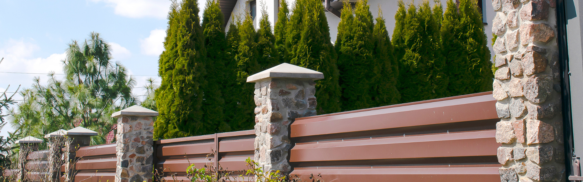 Decorative and durable residential fencing with stone pillars providing privacy and curb appeal.